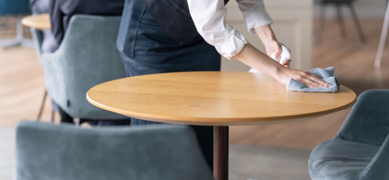 Wiping a restaurant table during commercial cleaning in Pompano Beach