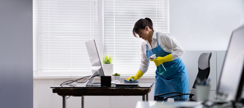Janitor cleaning a desk by the window for an office cleaning company in Pompano Beach