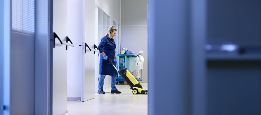 Janitor with a cleaning cart in a hallway providing janitorial services in Coral Springs