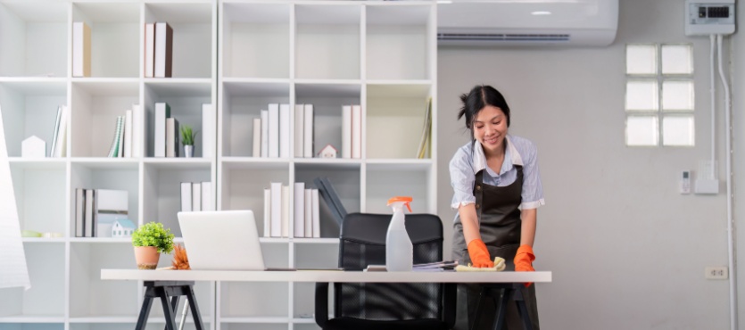 Woman cleaning an office desk during spring commercial cleaning in Pompano Beach
