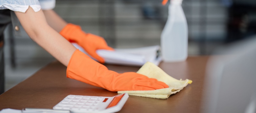 Sanitizing a desk with orange gloves during commercial cleaning in Fort Lauderdale