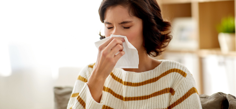 Woman sneezing from allergies that commercial cleaning in Pompano Beach helps reduce