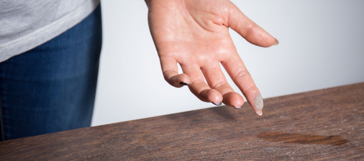 Finger checking a dusty desk before commercial cleaning in Delray Beach