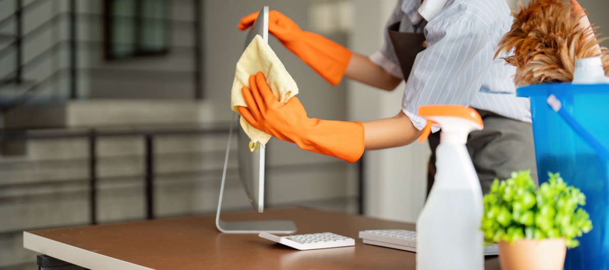 Worker in orange gloves disinfecting a desk during commercial cleaning in Plantation